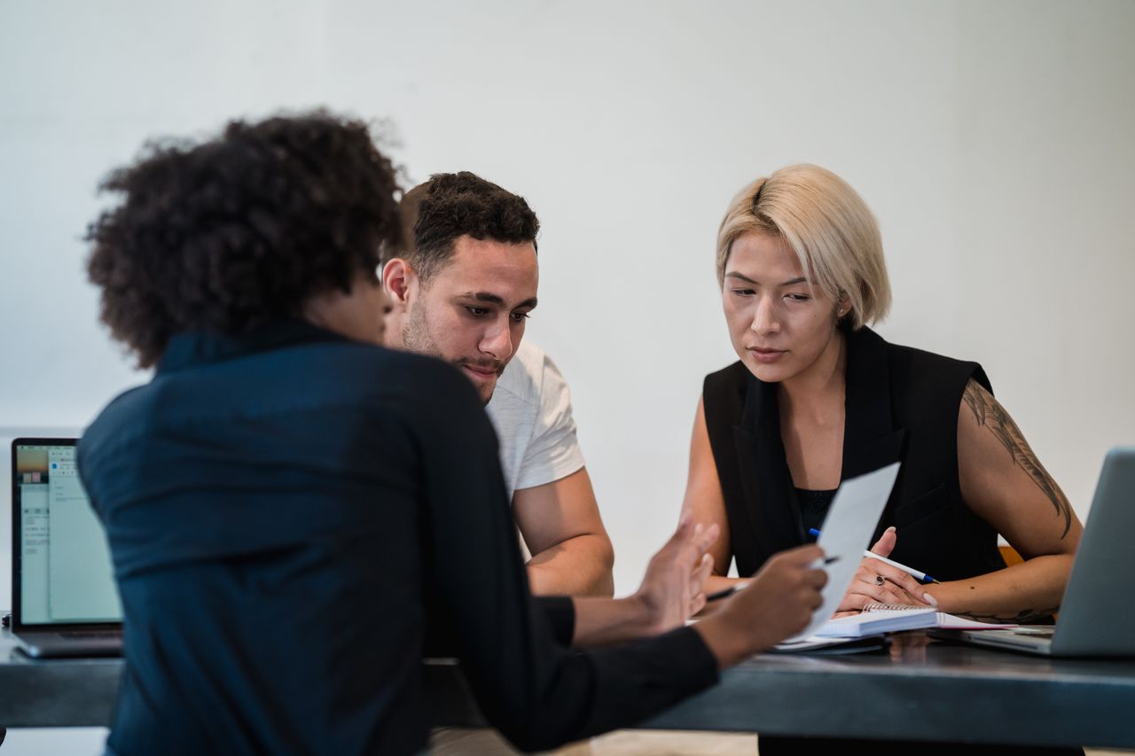 Diverse team engaged in a focused meeting at a contemporary workplace, discussing project details.
